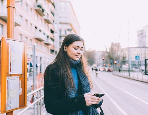 Woman looking at phone at bus stop